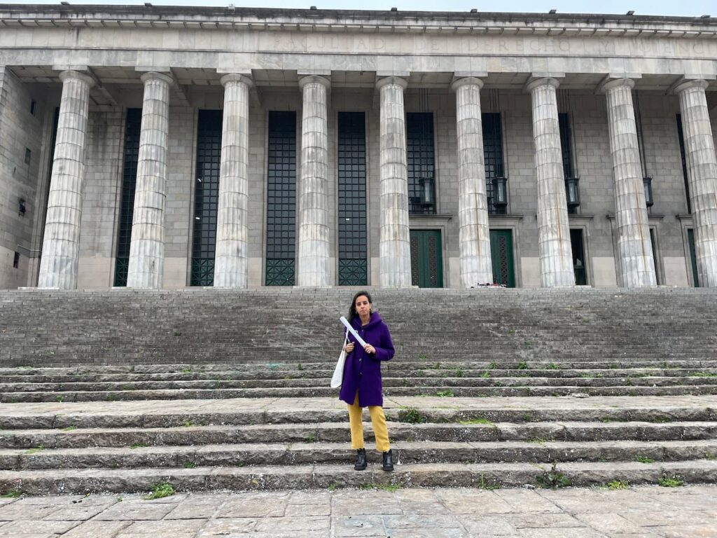 Gabi stepping down the stairs of her college with her diploma in her hands.